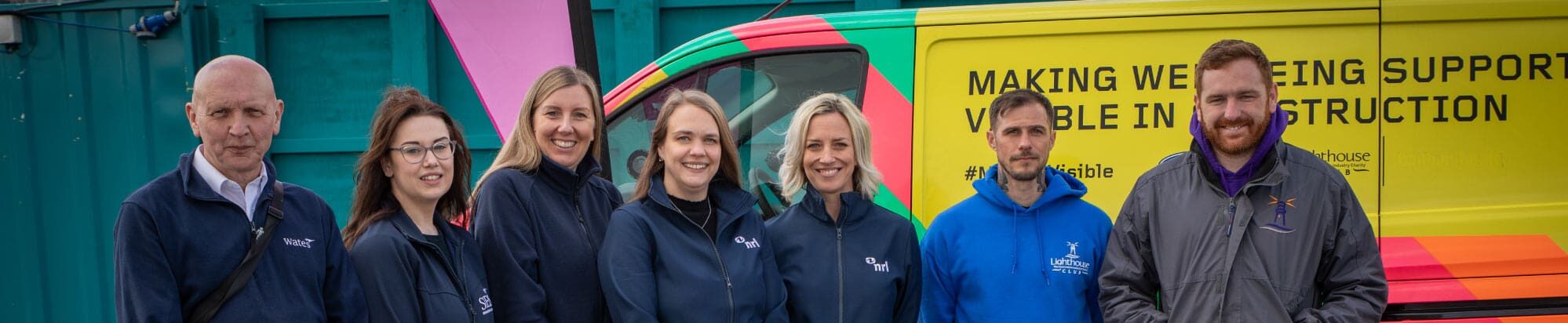 Sunderland colleagues and the Lighthouse Charity staff, stood in a line all smiling at the camer. The Lighthouse Charity van in the background